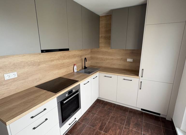 Küche in einer 2-Zimmer-Wohnung mit Holzschränken und dunklen Fliesen.