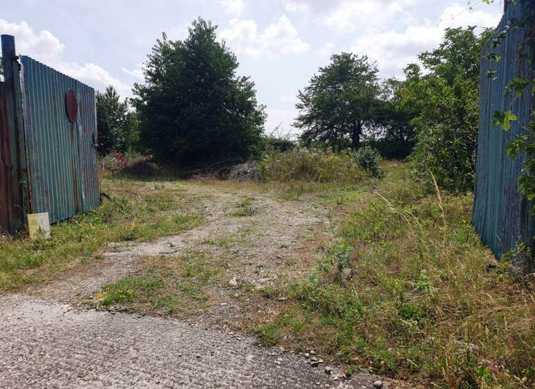 Eingezäunter Zugang zu Gewerbegrundstücken in Trenčianske Bohuslavice mit Grünflächen und Gehweg.