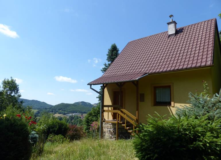 Eine Hütte in Štiavnické Bane, umgeben von Grün und mit Blick auf die Hügel im Hintergrund.