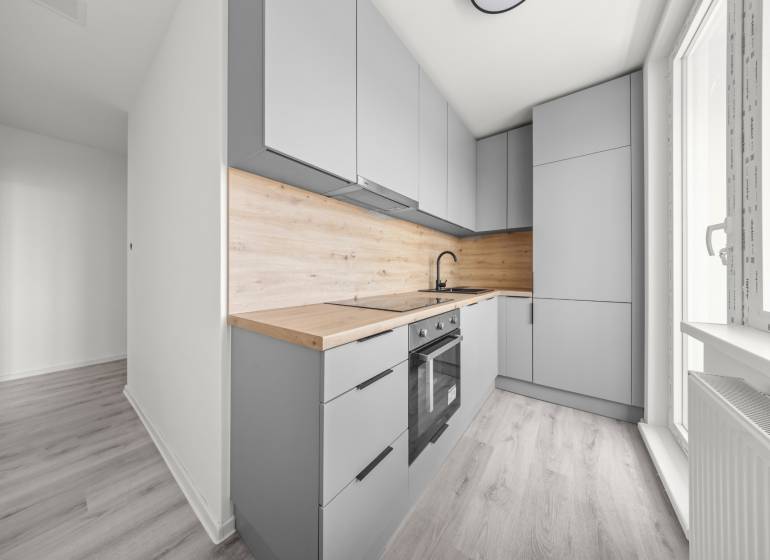 Helle Küche mit Holzarbeitsplatte in einer Zweizimmerwohnung.
