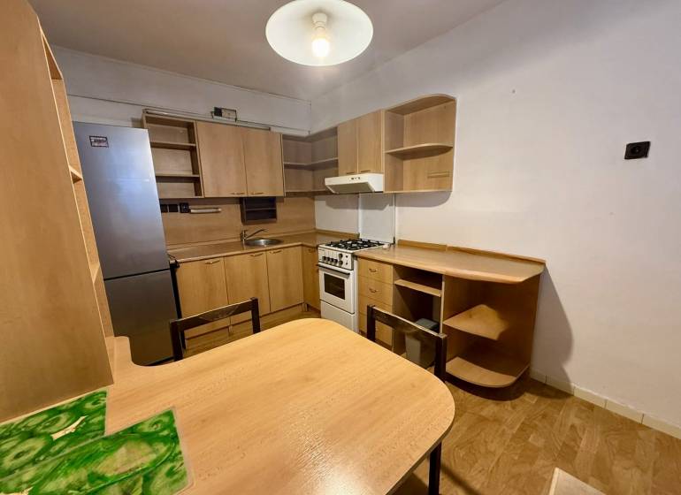 Küche in einer Einzimmerwohnung ausgestattet mit Holzmöbeln und einem Kühlschrank.