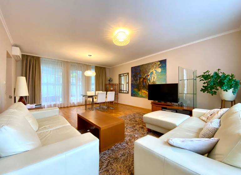 Wohnzimmer in einer 3-Zimmer-Wohnung mit hellen Sofas, Fernseher und Esstisch.