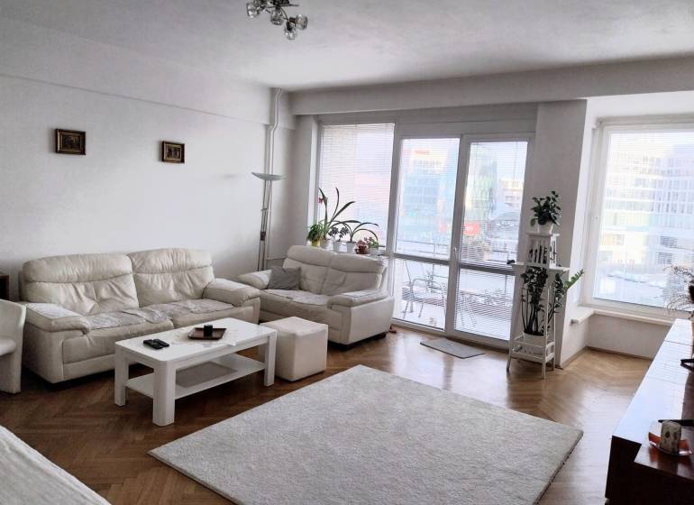 Helles Wohnzimmer mit weißen Sofas in einer 4-Zimmer-Wohnung, Glastüren zur Terrasse.