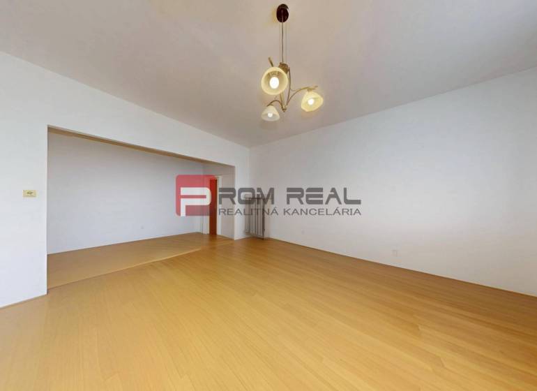Ein geräumiges Zimmer mit Holzboden und einer Leuchte in einer 3-Zimmer-Wohnung.