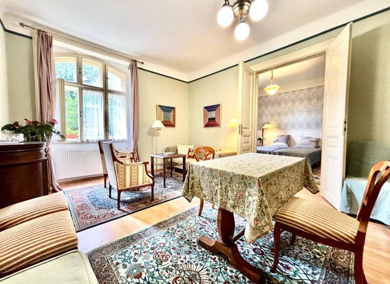 Traditionelles Interieur einer 2-Zimmer-Wohnung mit Teppich, Möbeln und Zimmerpflanzen.