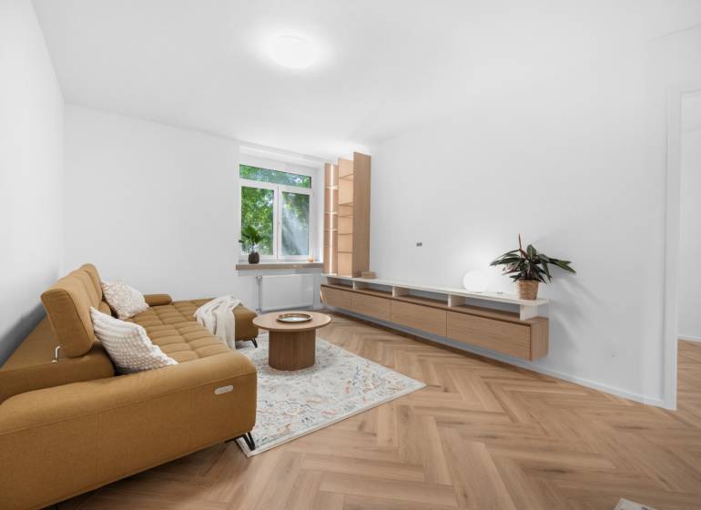Wohnzimmer in einer 3-Zimmer-Wohnung mit Sofa, Couchtisch und Holzboden.