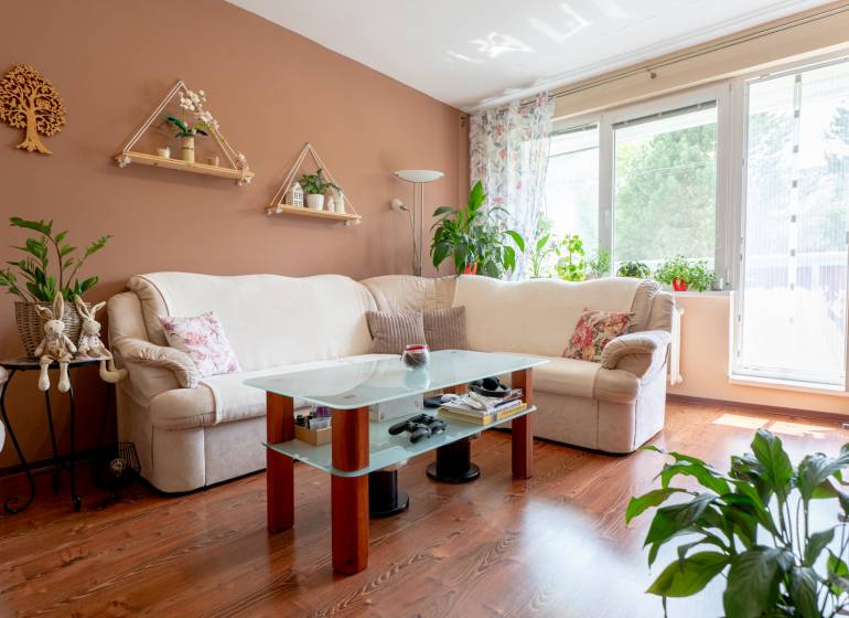 Helles Wohnzimmer in einer 3-Zimmer-Wohnung mit Blumendekoration und bequemer Couch.