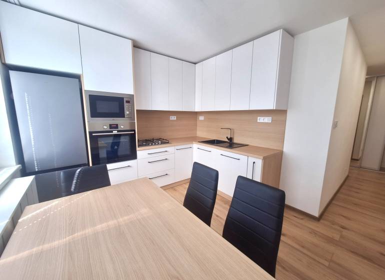 Küche in einer 2-Zimmer-Wohnung mit modernen Möbeln, Geräten und einem Esstisch.