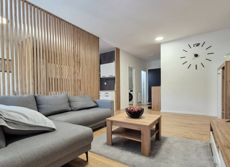 Ein stilvolles Wohnzimmer in einer 4-Zimmer-Wohnung mit Holzverkleidung, einem bequemen Sofa und einem Tisch.