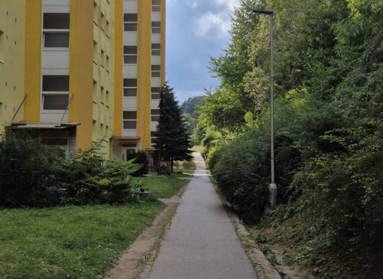 Gelbes Wohnhaus in der Moskauer Straße in Banská Bystrica neben dem Gehweg und dem Grün.