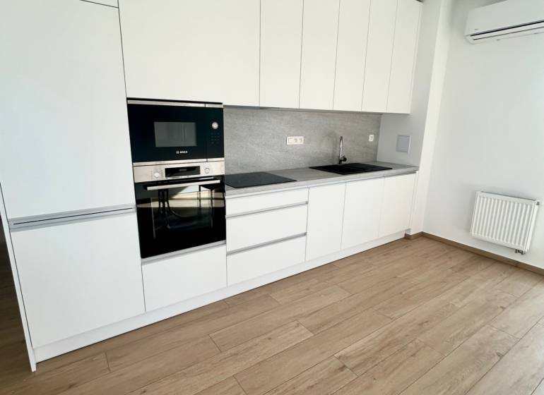 Küche in einer 3-Zimmer-Wohnung mit weißen Schränken, Geräten und Holzboden.