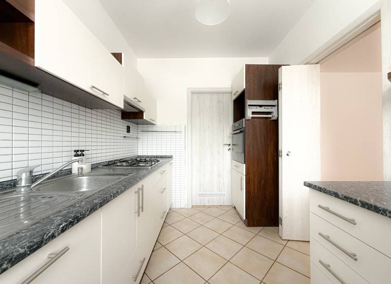 Küche einer 3-Zimmer-Wohnung mit gefliester Wand, Doppelspüle und eingebautem Ofen.