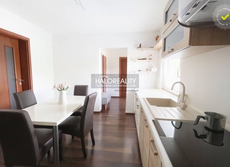 Kücheninterieur eines Einfamilienhauses mit Esstisch und Boden in Holzdekor.
