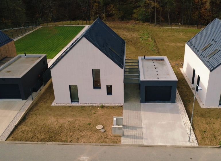Einfamilienhäuser in der Straße Pod Drieňovou in Kamenica nad Cirochou, umgeben von Rasen und Zufahrtsstraße.