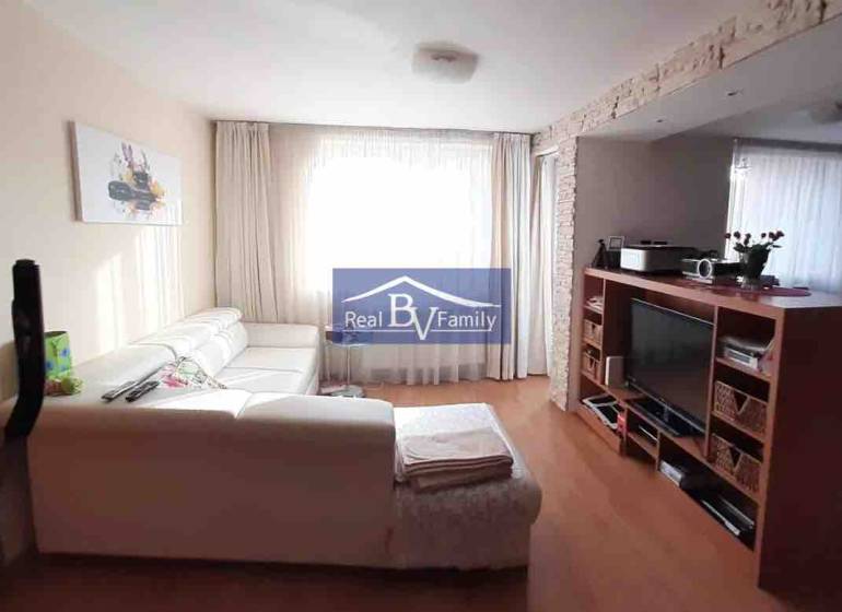 Wohnzimmer mit weißem Sofa und Fernseher, Holzboden, 2-Zimmer-Wohnung.