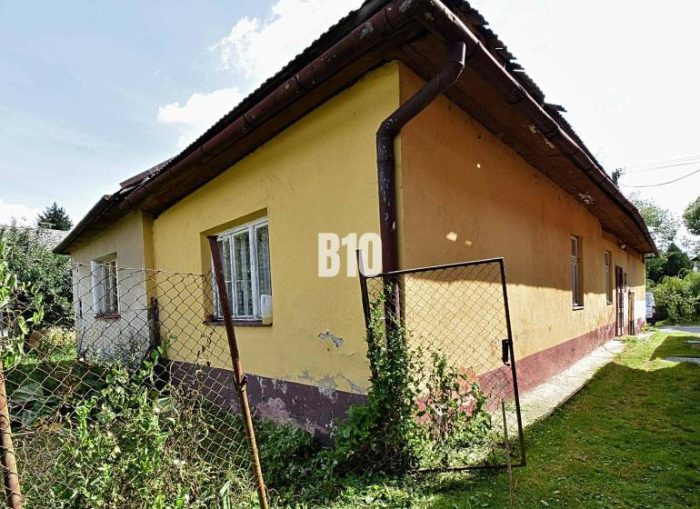 Ein Einfamilienhaus in Partizánska Ľupča, gelbe Fassade, alter Zaun mit Maschendraht.