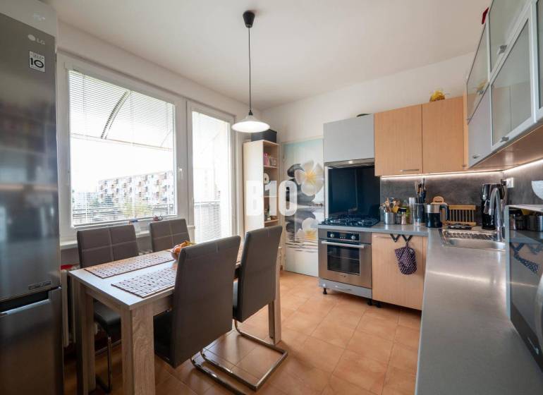 Küche in einer 4-Zimmer-Wohnung mit Esstisch, braunen Stühlen und großem Fenster.