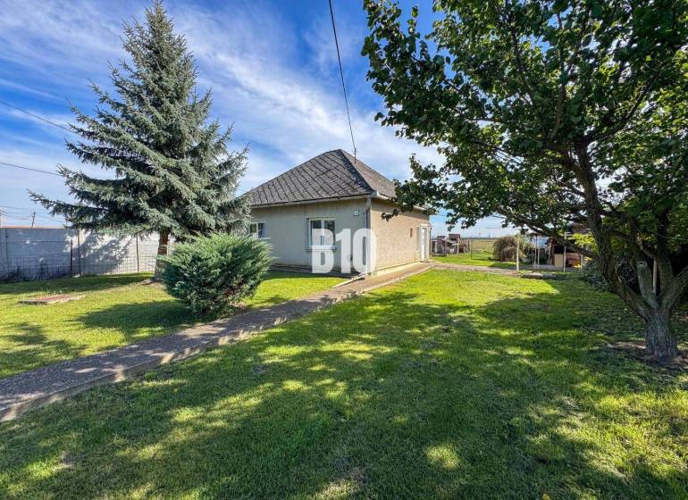 Ein Einfamilienhaus in Ondrejovce, umgeben von grünem Rasen und Bäumen in einem geräumigen Garten.