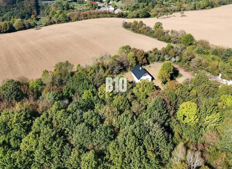 Eine Hütte in Lackov, umgeben von Wald und Feldern, eine ruhige ländliche Landschaft.