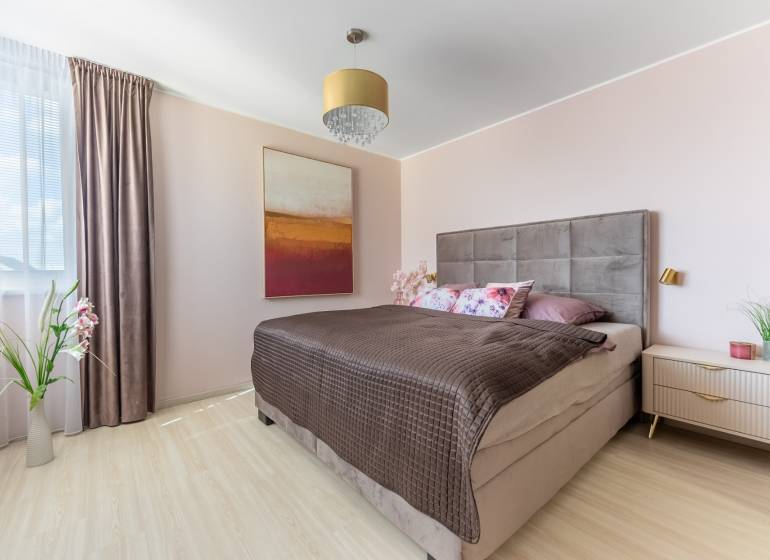 Schlafzimmer in einem Einfamilienhaus mit Bett, Bild, Lampe und Boden mit Holzdekor.