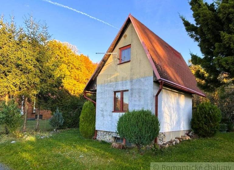 Ein Ferienhaus in Sološnica, umgeben von Grün, mit einem Satteldach und gepflegtem Rasen.