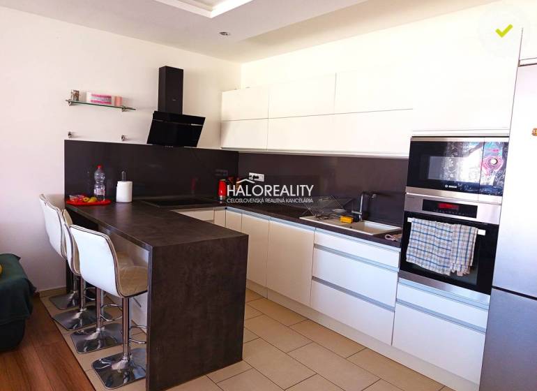 Eine Küche mit weißen Schränken und einer Bartheke in einer 3-Zimmer-Wohnung.