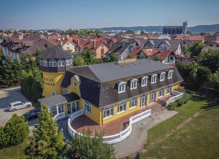 Gelbes Hotel mit Turm, umgeben von einem Garten in der Stadt Poprad, Hotels und Pensionen.