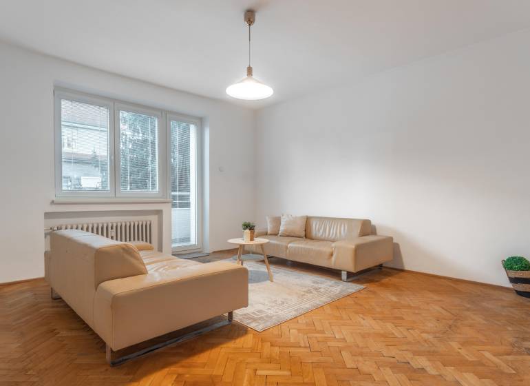 Wohnzimmer in einer 3-Zimmer-Wohnung mit beigen Sofas und einem Boden in Holzoptik.