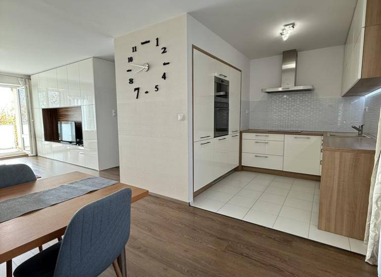 Essbereich in einer 4-Zimmer-Wohnung mit Holzboden und Küche im Hintergrund.