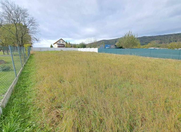 Grundstück mit Gras, Bäumen, geeignet zum Wohnen, eingezäunt, Haus im Hintergrund.