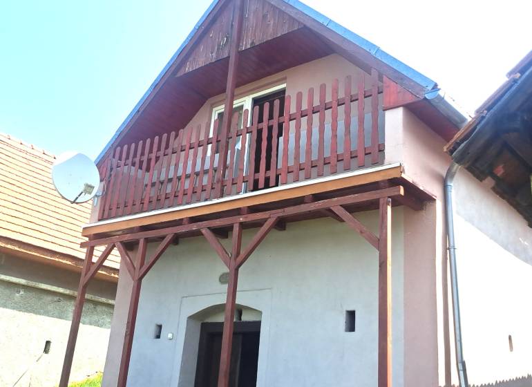 Ein Ferienhaus in Hontianske Trsťany mit einem Holzbalkon und einer Satellitenschüssel.