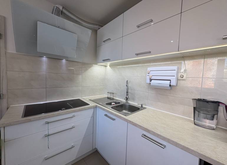 Küche mit eingebautem Kochfeld und Spüle in einer 3-Zimmer-Wohnung.