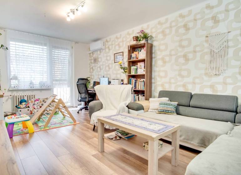 Wohnzimmer in einer 3-Zimmer-Wohnung mit Holzboden und Arbeitsecke.