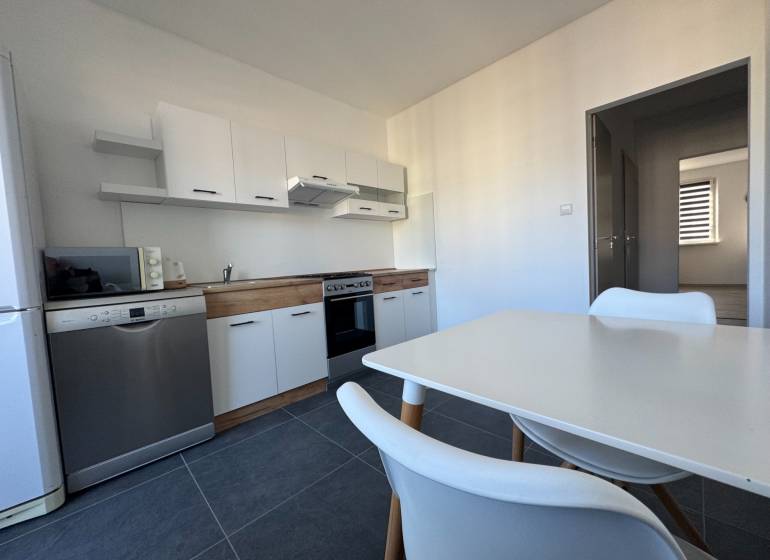 Die Küche einer 3-Zimmer-Wohnung mit weißen Möbeln und Geräten, Boden aus Keramikfliesen.