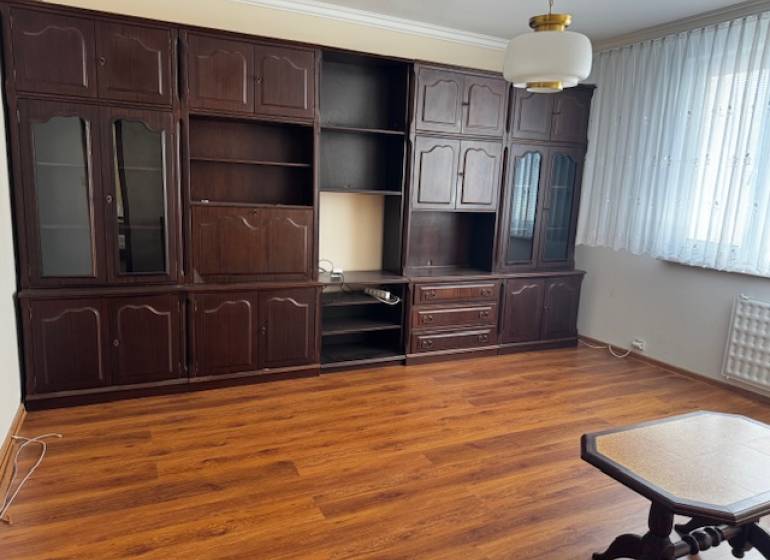 Wohnzimmer in einer 3-Zimmer-Wohnung mit Holzboden und dunklen Möbeln.