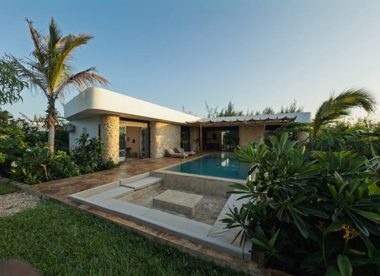 Ein Einfamilienhaus in Paje, Region Unguja South, mit einem Pool, umgeben von üppiger Vegetation und Pflastersteinen.
