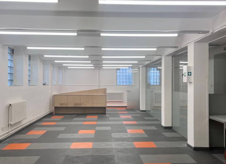 Gewerberäume mit farbigem Boden und verglasten Trennwänden, geeignet für Büros oder Betriebe.