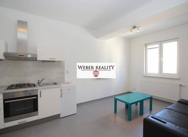 Küche in einer 2-Zimmer-Wohnung mit grauem Boden, Küchenzeile und Sitzgelegenheiten.