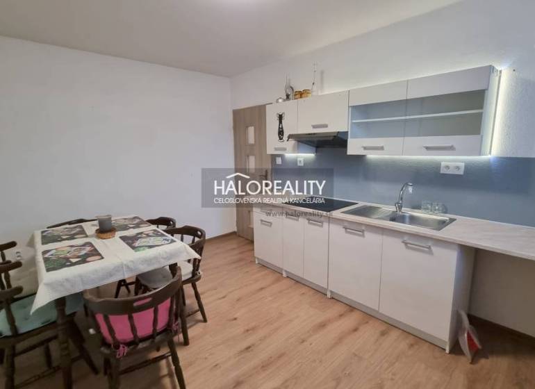 Ein Einfamilienhaus in Poprad mit Rasen, Holzzaun und Nadelbäumen im Hintergrund.