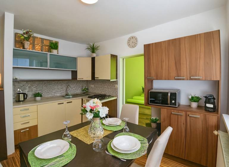 Küche in einer Einzimmerwohnung mit Esstisch und Boden in Holzoptik.