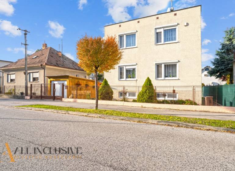 Einfamilienhäuser in Dunajská Streda, von Bäumen gesäumte Straßen, Gitterzäune, blauer Himmel.