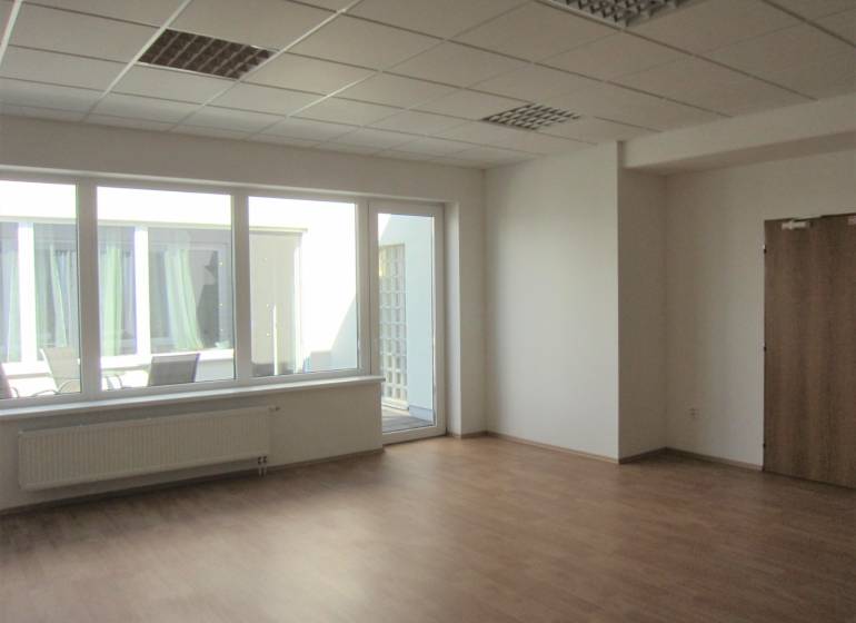 Ein geräumiges Büro mit großen Fenstern und einem Boden in Holzoptik.