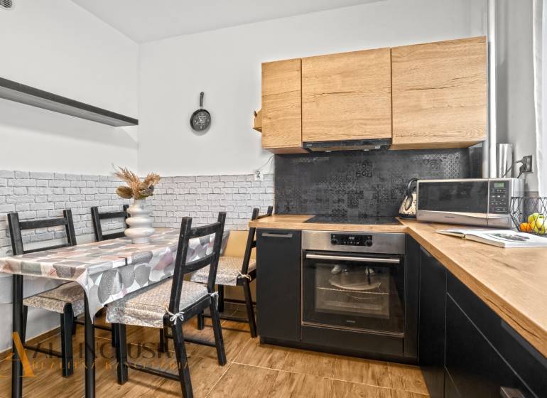 Eine Küche mit Holzdekor, Esstisch und Geräten in einer 3-Zimmer-Wohnung.