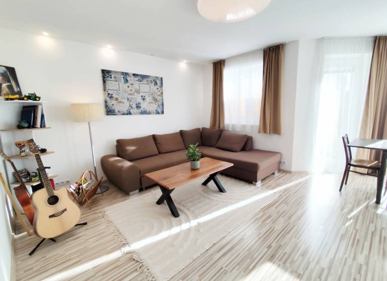 Wohnzimmer in einem Einfamilienhaus mit großem Sofa und Boden in Holzoptik.