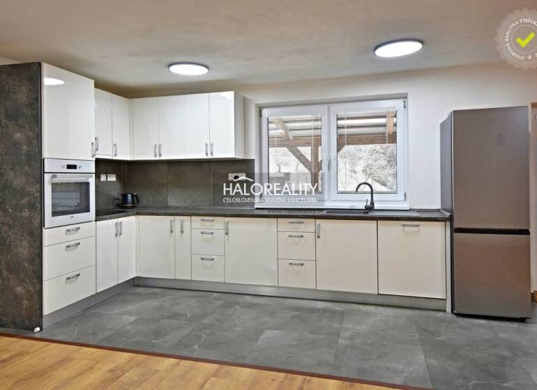 Eine Küche in einem Einfamilienhaus mit modernen Geräten und einem Boden in Holzoptik.