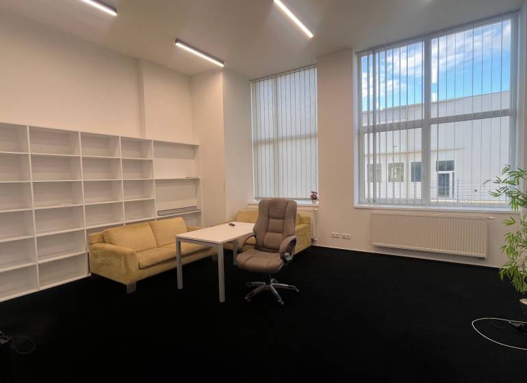 Büros mit schwarzem Teppich, Möbeln, Regalsystemen und großen Fenstern.