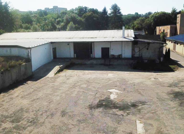 An der Straße Železničná befinden sich Lagerhallen, umgeben von Grünflächen, die zur Nutzung geeignet sind.