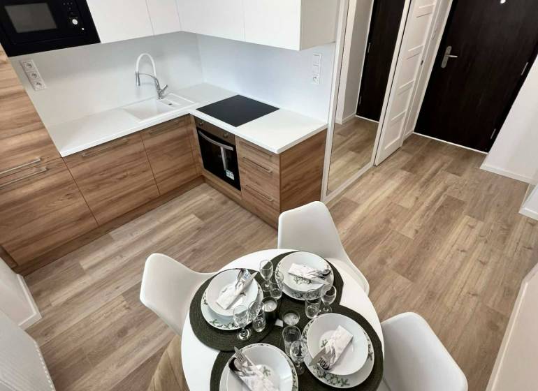 Küche in einer 2-Zimmer-Wohnung mit Holzboden und Esstisch.