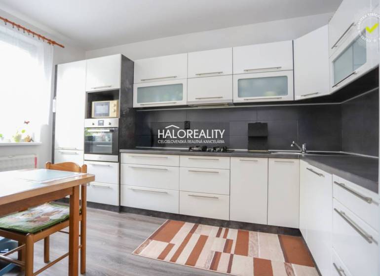 Küche in einer 3-Zimmer-Wohnung mit weißen Schränken und einem Boden in Holzoptik.