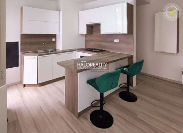 Küche in einer 2-Zimmer-Wohnung mit Bartresen, grünen Stühlen und Holzboden.